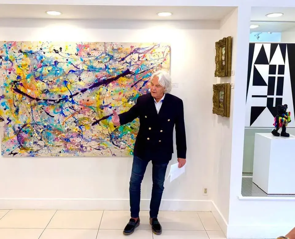 The contemporary artist beside one of his paintings in a gallery