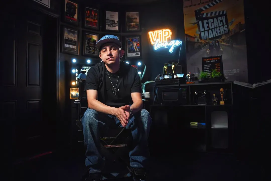 Manuel Aragon seated in a lounge with neon signs behind him