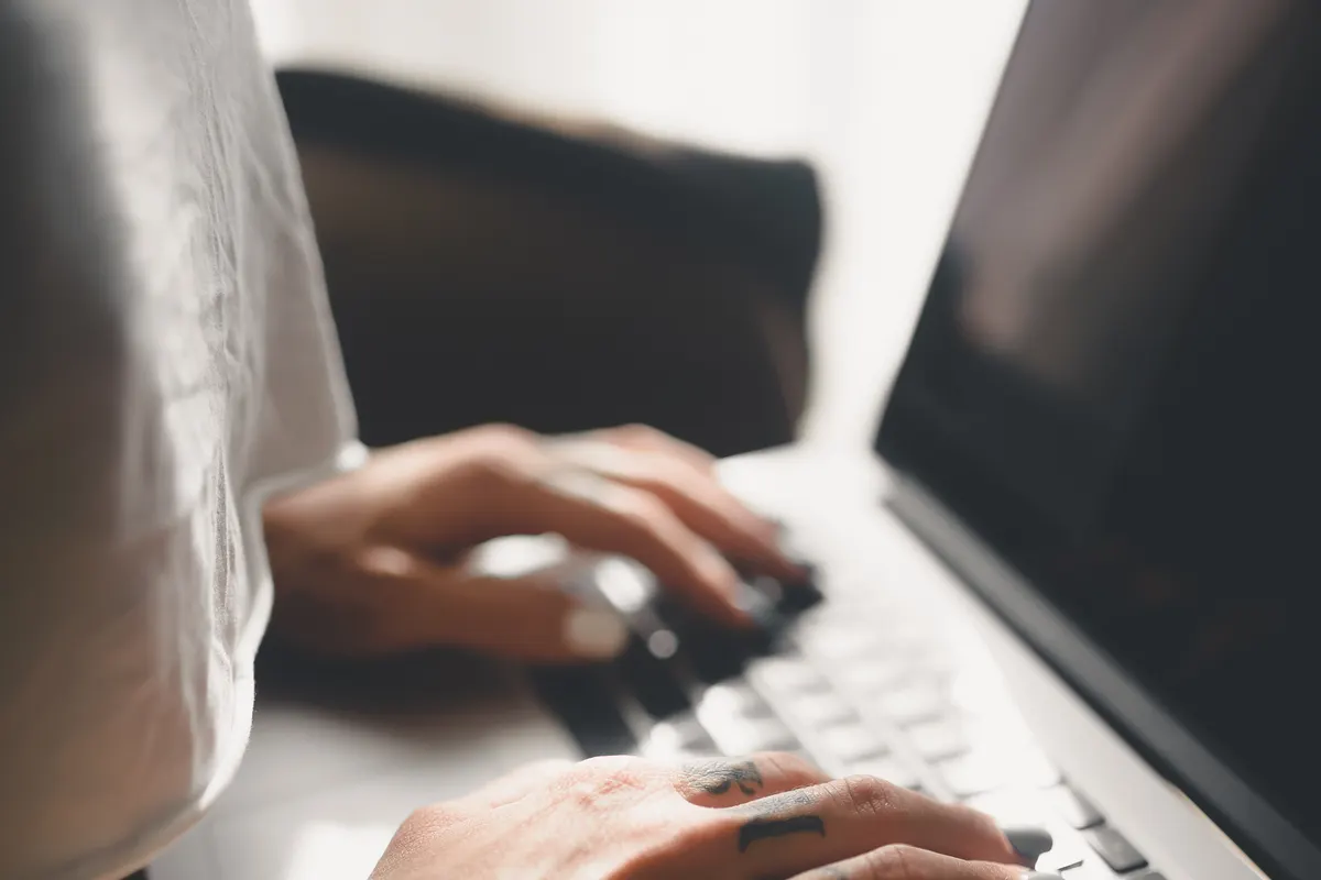 Hands typing on a laptop keyboard as someone asks a question that an AI assistant answers