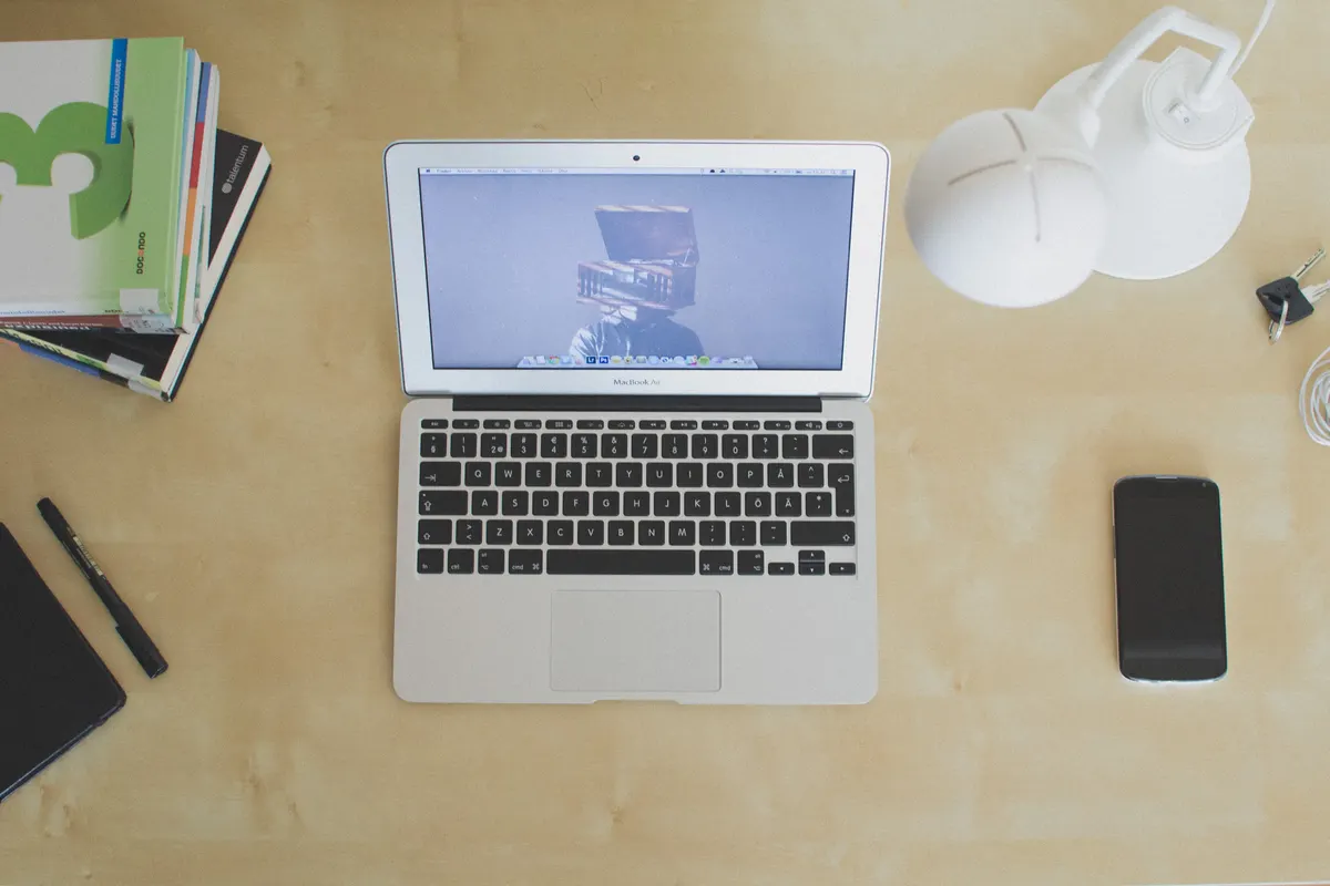 A laptop on a desk with books and a phone ready for a brand name search
