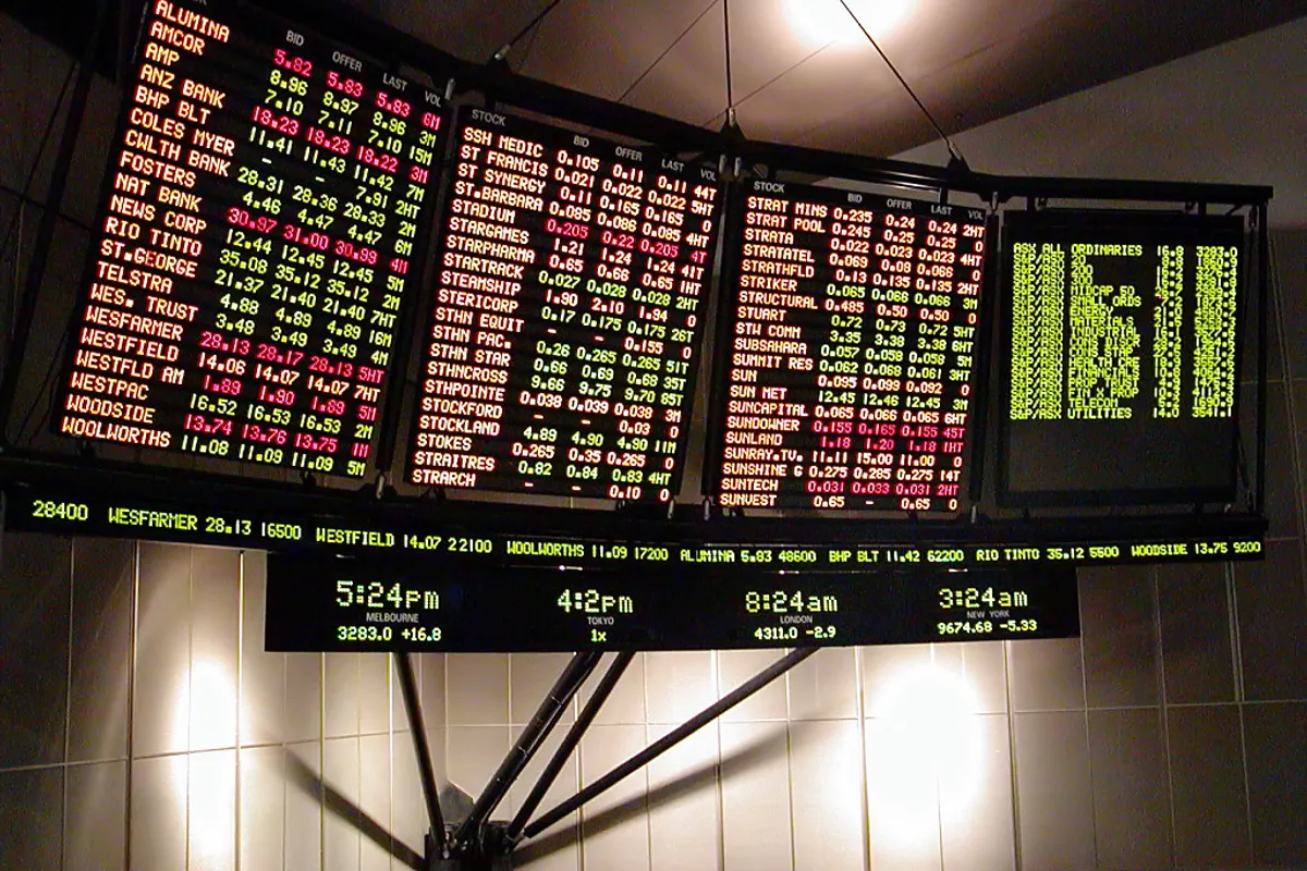 Illuminated stock exchange boards listing company prices above a scrolling ticker line