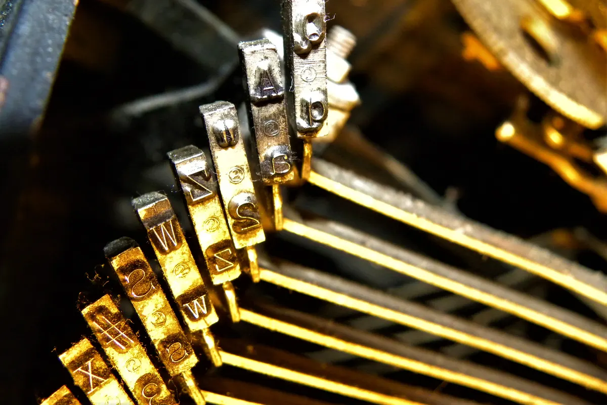 Close-up of the brass letter keys on the typebars of a vintage typewriter