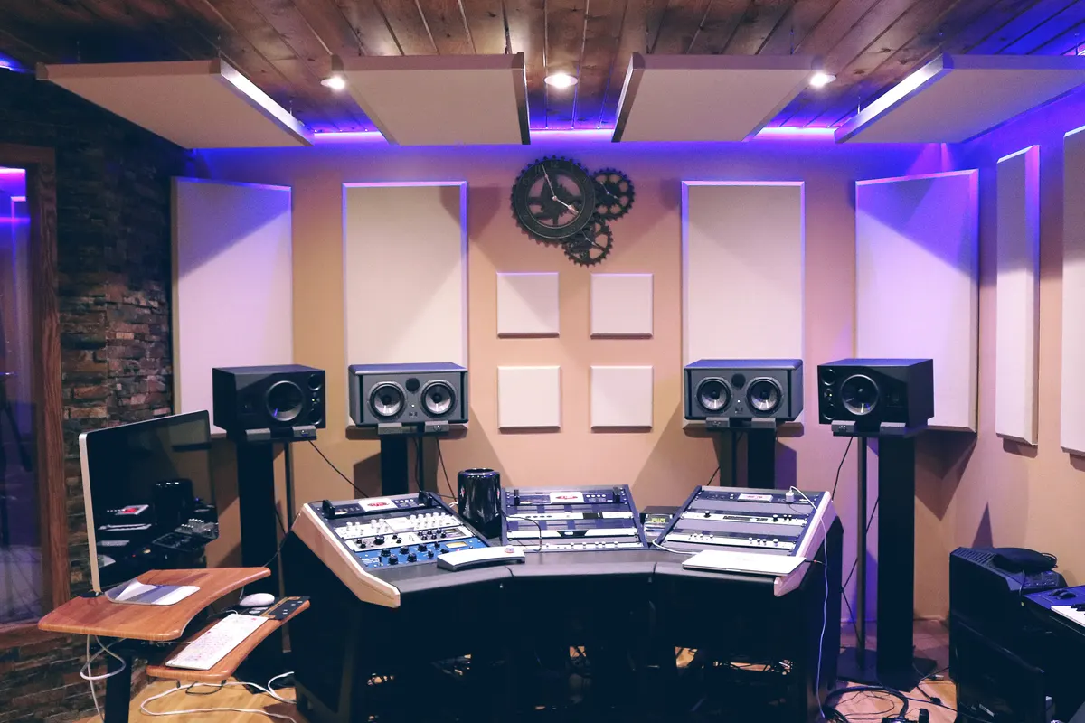 A recording studio control room with monitor speakers on stands and a mixing desk