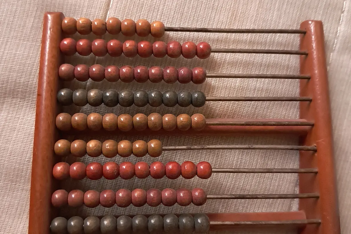 A wooden abacus with rows of red and brown beads pushed along thin rods